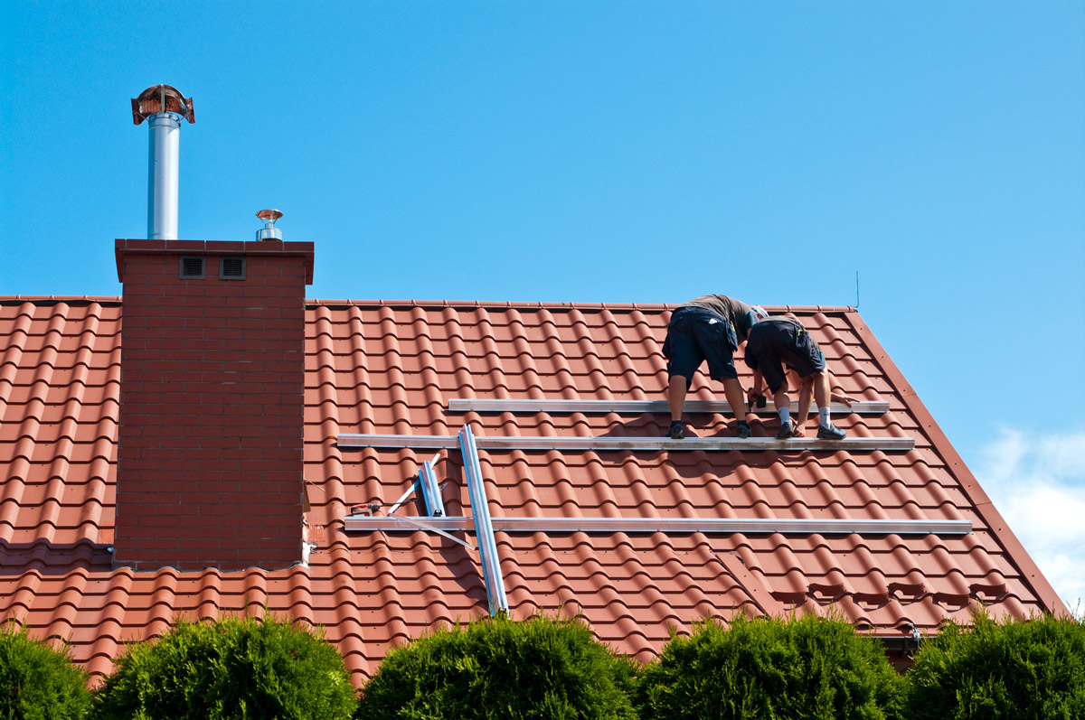 Two men installing residential solar panels on roof of home